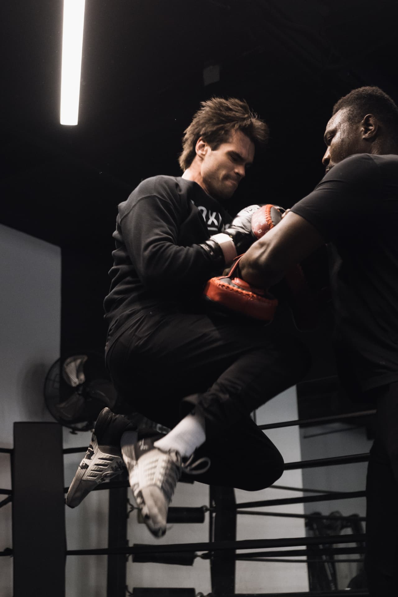Trainer holding focus mitts for a boxer in a ring